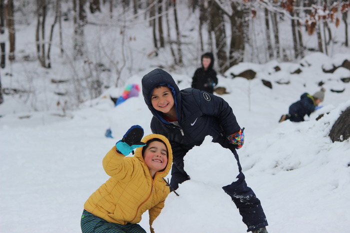 Two Sant Bani students build a snowman